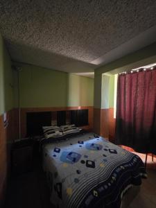 a bedroom with a bed with a blanket on it at EL BOSQUE Hostal in Chiclayo