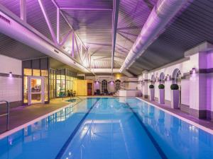 a large swimming pool with blue water in a building at Mercure Exeter Southgate Hotel in Exeter