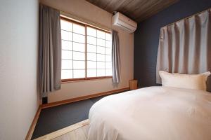 a bedroom with a white bed and a window at 民泊-天- in Beppu