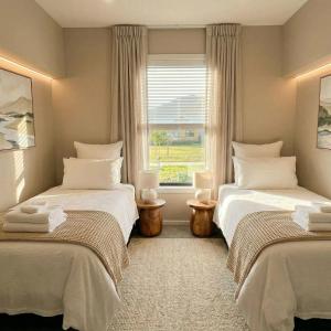 two beds in a room with a window at Mount Pisa View Stay - Barnd new holiday home in Cromwell