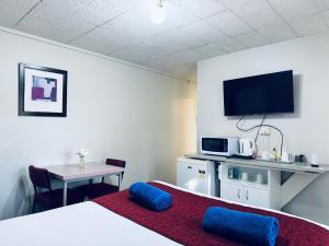 a hotel room with a bed and a table and a tv at Edinburgh Motor Inn in Warragul