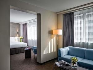 a hotel room with a blue couch and a bed at Pullman Paris Tour Eiffel in Paris