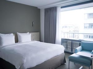 a bedroom with a large white bed and a blue chair at Pullman Paris Tour Eiffel in Paris