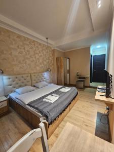 a bedroom with a large bed and a television at Happy Stay Hotel in Kutaisi