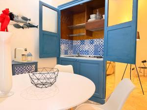 a kitchen with blue cabinets and a white table and chairs at Suite Del Borgo in Gallipoli +25 photos