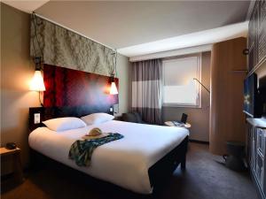 a hotel room with a large bed with a hat on it at ibis Les Herbiers in Les Herbiers