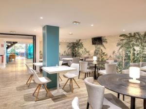 a restaurant with tables and chairs and plants on the wall at ibis Styles Saint Julien en Genevois accès espace aquatique UCPA Vitam INCLUS in Neydens