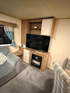 a living room with a flat screen tv and a couch at haggerston castle lakeside east 27 in Goswick Station