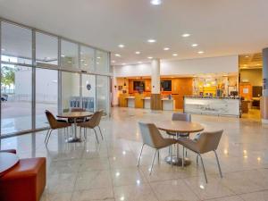 a lobby with tables and chairs in a building at ibis Vitoria Praia de Camburi in Vitória