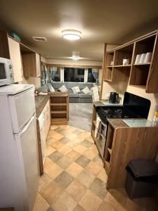 a small kitchen with a couch in the background at haggerston castle lakeside east 27 in Goswick Station +8 photos