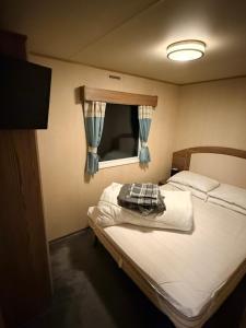 a small bedroom with a bed and a window at haggerston castle lakeside east 27 in Goswick Station