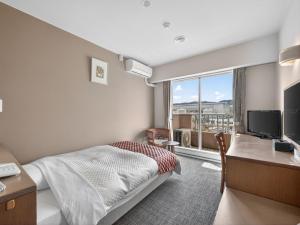 a hotel room with a bed and a desk and a window at Hitachi Ocean View HOTEL and RESORT in Hitachi