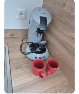 a coffee maker and two red cups on a counter at Le petit duo in Saint-Brieuc