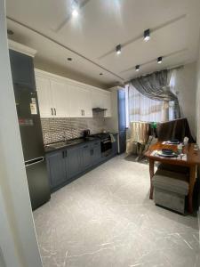 a kitchen with white cabinets and a table in it at Luxanda Samarkand in Samarkand