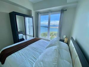 a bedroom with a large bed and a large window at Pacific Staycation in Kaybagal