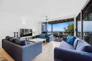 a living room with two blue couches and a balcony at Cylinder Cove 9 in Point Lookout