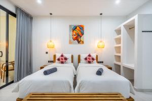two beds in a room with white walls at Dreamland Suites - Walk to Dreamland Beach in Uluwatu