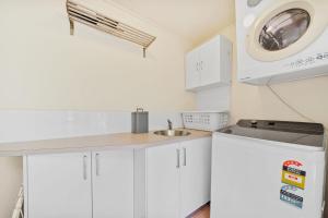a white kitchen with a sink and a microwave at Dragonflies on Billa in Point Lookout +14 photos