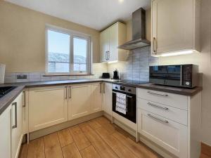 a large kitchen with white cabinets and a window at The Annexe - Uk51362 in Dollar