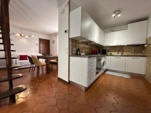 a kitchen with white cabinets and a dining room with a table at La casa di Carlotta in Loano