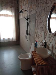 ein Badezimmer mit Waschbecken, Toilette und Spiegel in der Unterkunft Kitabi EcoCenter in Kitabi
