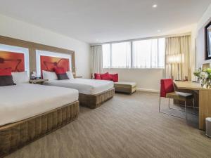 a hotel room with two beds and a desk at Novotel Sydney West HQ in Rooty Hill