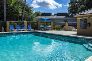 a swimming pool with chairs and an umbrella at Econo Lodge Palm Coast Central in Palm Coast