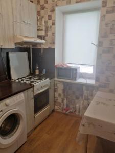 a kitchen with a stove and a washing machine at Квартира in Sumy