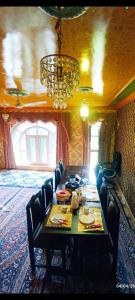 ein Esszimmer mit Tisch, Stühlen und Kronleuchter in der Unterkunft De brook in Srinagar