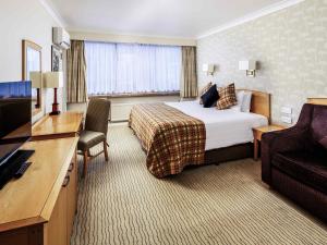 a hotel room with a bed and a flat screen tv at Mercure Norwich Hotel in Norwich