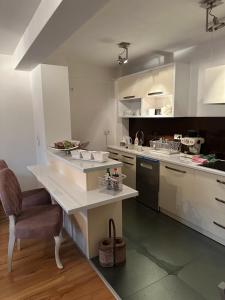a kitchen with white cabinets and a table and a chair at alisa in Srebrenik