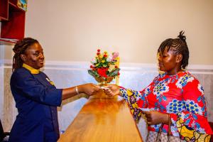 a woman is handing a woman a vase of flowers at West Hotel Douala in Bonabéri