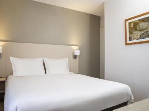 a large white bed in a hotel room at Aparthotel Adagio Access Avignon in Avignon +54 photos