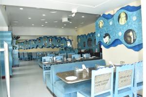 a dining room with blue chairs and a table at Hotel Samrat International in Mount Ābu