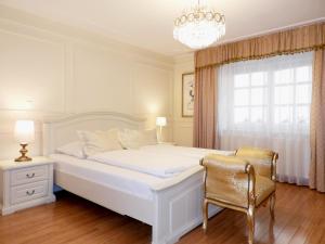 a white bedroom with a bed and a chair at Allegro Hotel in Ljubljana