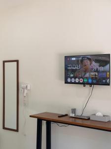 a flat screen tv hanging on a wall next to a table at Wanwichai Room in Ban Lam Ru (1)