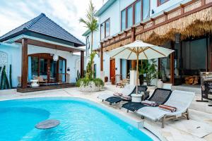 a swimming pool with two lounge chairs and an umbrella at Casa Maddu in Tegalalang