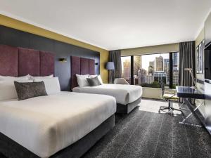 two beds in a hotel room with a view at Pullman Sydney Hyde Park in Sydney
