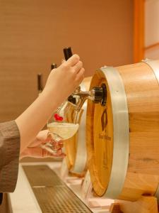 a person pouring a drink into a wine barrel at Hana Beppu in Beppu