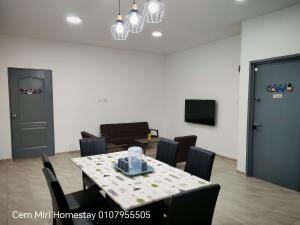 a dining room with a table and chairs and a tv at Cem Miri Homestay 2 in Miri