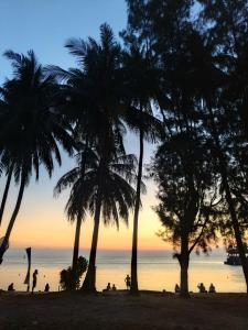 a group of people on a beach with palm trees at Maya Sunset Room, Coral Bay Perhentian Island in Perhentian Island