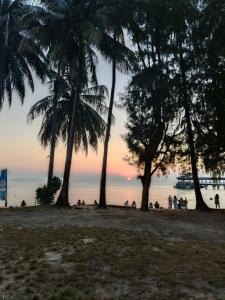a group of people on a beach with palm trees at Maya Sunset Room, Coral Bay Perhentian Island in Perhentian Island