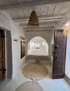 a bedroom with a bed and a chandelier at Hoûch Les Anartistes in Erriadh