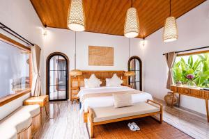 a bedroom with a bed and a couch and windows at Sake Bali Suites in Tegalalang +65 photos