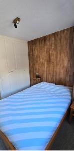 a bedroom with a blue bed with a wooden wall at Charmant petit appartement in Ovronnaz