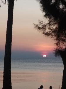 two people sitting on the beach watching the sunset at Maya Seaview Chalet, Coral Bay Perhentian Island in Perhentian Island