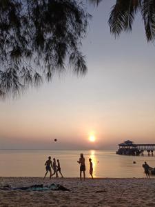 a group of people playing frisbee on the beach at sunset at Maya Seaview Chalet, Coral Bay Perhentian Island in Perhentian Island +26 photos