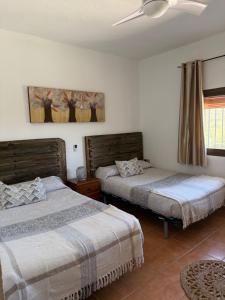 a bedroom with two beds and a ceiling fan at Cortijo Loma del Estanque in Monachil +36 photos