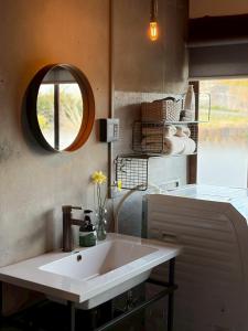 a bathroom with a white sink and a mirror at ノキシタ in Hokuto