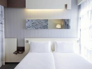 ein weißes Bett mit weißen Kissen in einem Schlafzimmer in der Unterkunft Ibis Styles Roma Eur in Rom